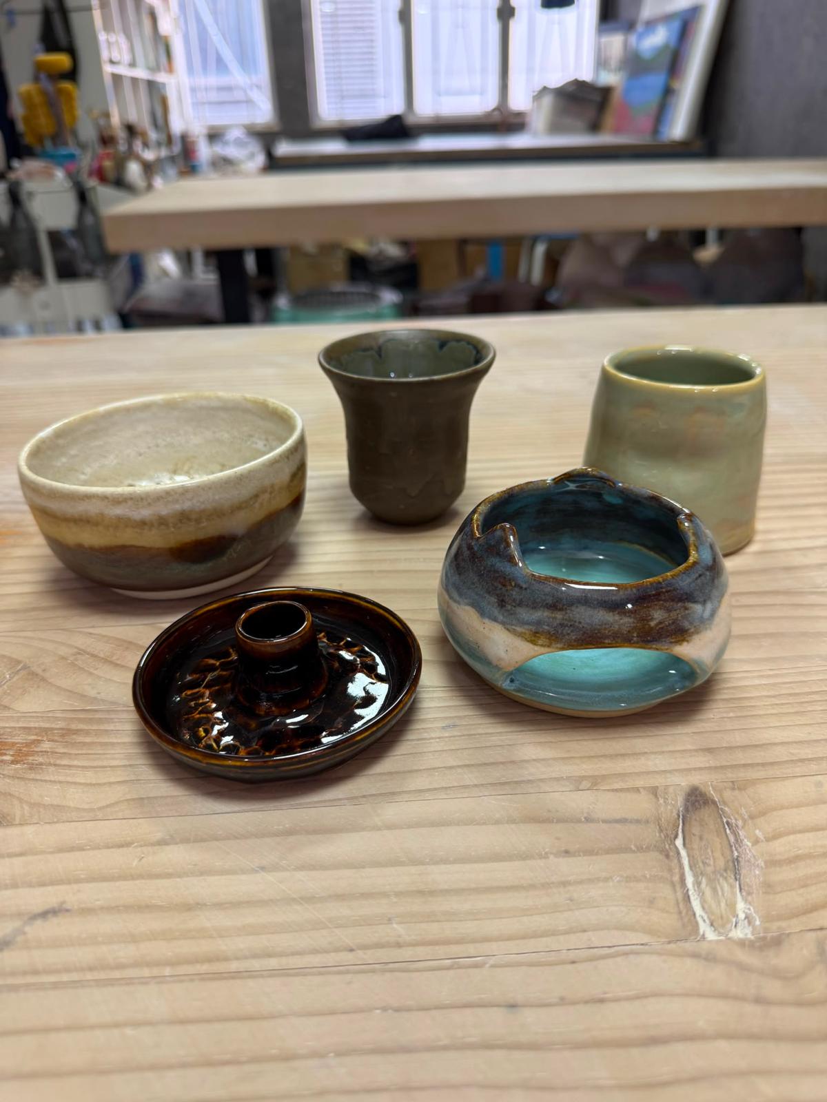 五件手工陶瓷作品：奶油紋大碗、墨綠小杯、鼠尾草綠杯、湖水藍缽、赤陶蓋碟，放喺工作枱上